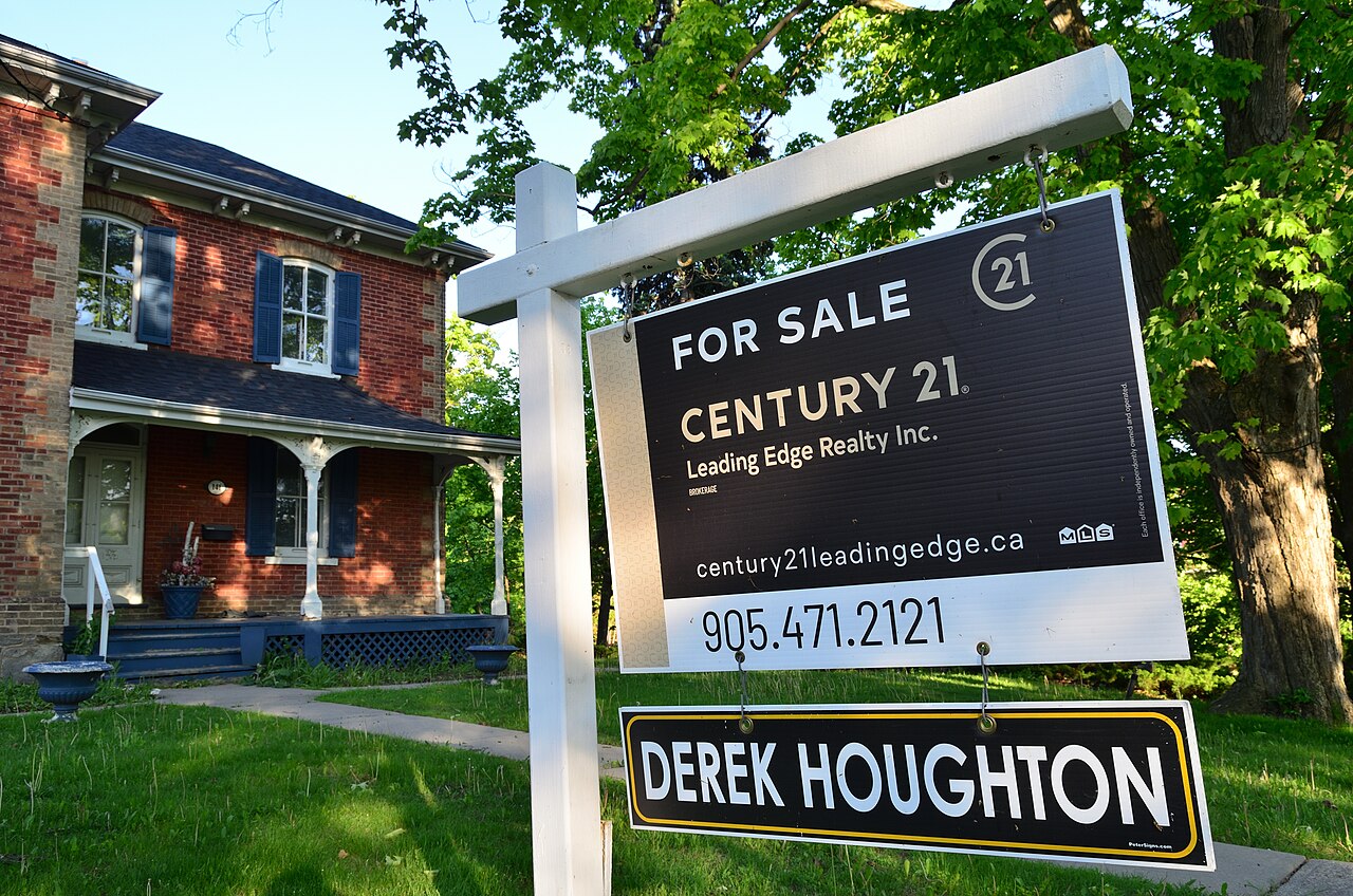A for-sale sign in front of a single-family home